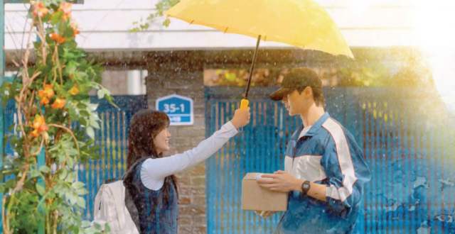 Byeon Woo Seok and Kim Hye Yoon, stars of Korean drama "Lovely Runner," under a yellow umbrella are depicted in a poster.